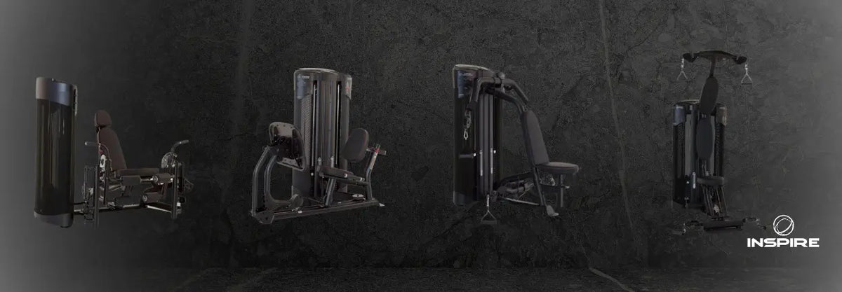Row of black Inspire Dual Stations strength machines in a dark room
