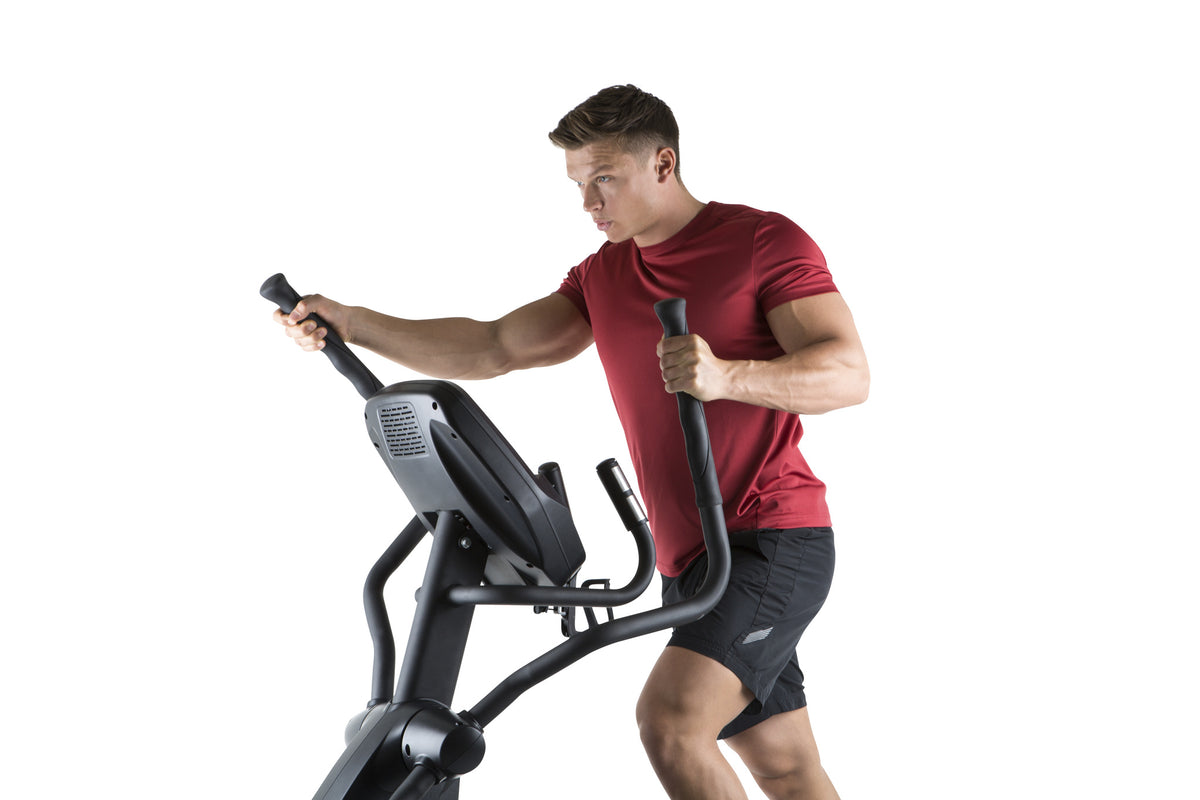 Man exercising on a cross trainer against a white background