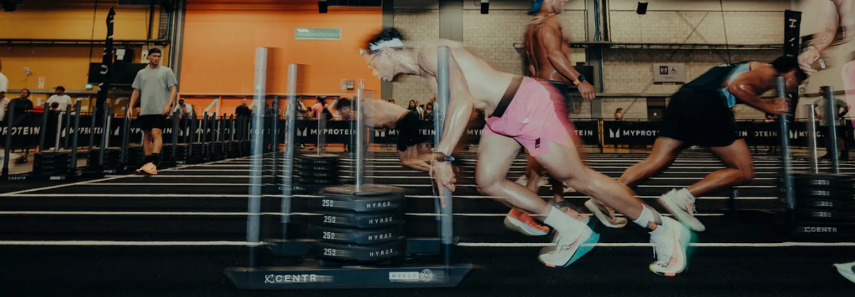 Atleten lopen tussen trainingsstations tijdens een indoor fitnesswedstrijd