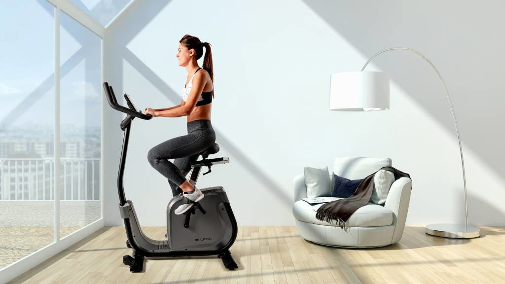 Woman cycling on an exercise bike beside a massage chair