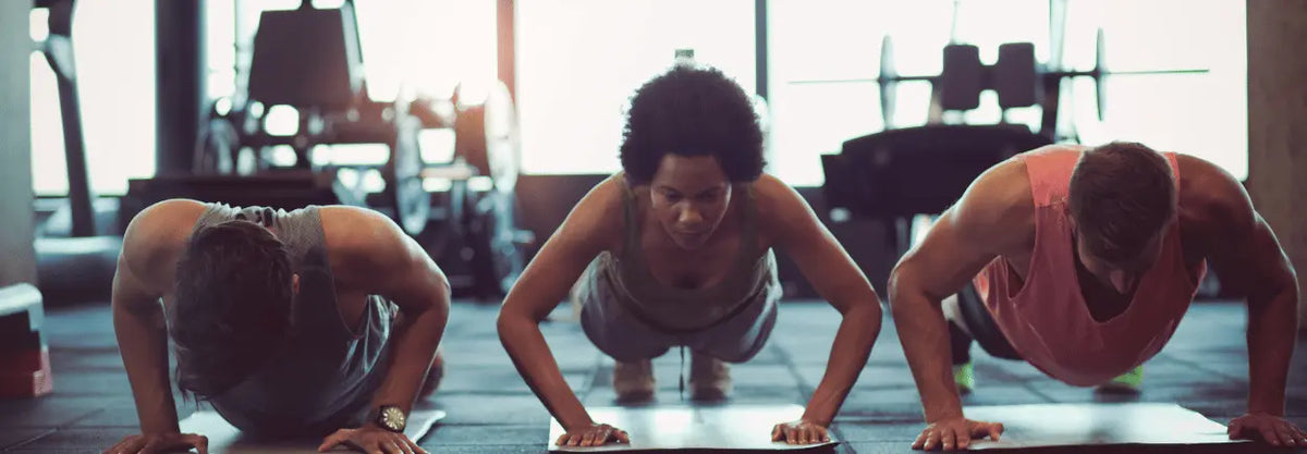 Two people doing push-ups side by side in a gym