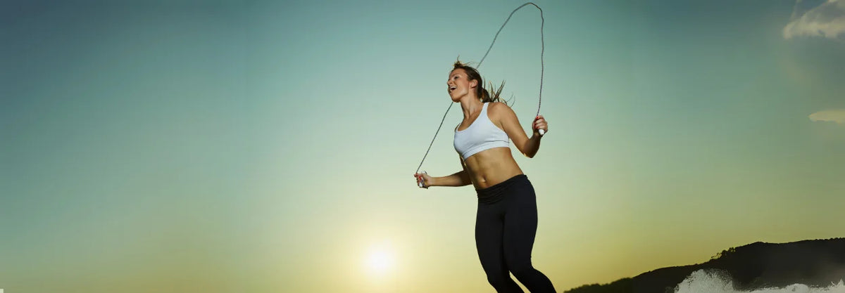 Woman skipping rope outdoors in low sunlight