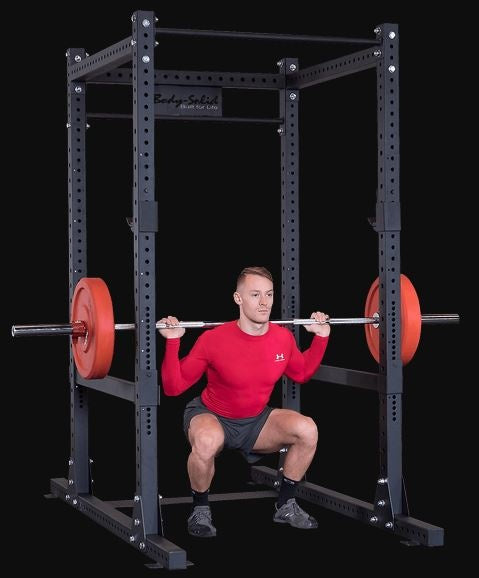 Man doet een squat met halterstang in het Body-Solid power rack