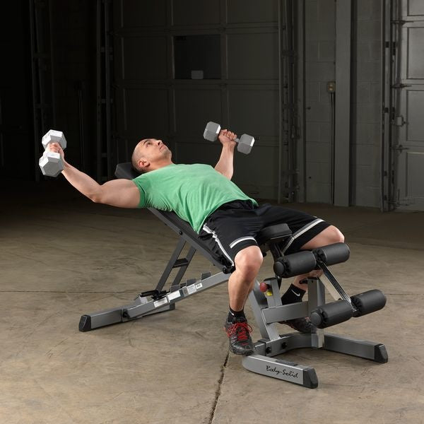 Man ligt op een schuin ingestelde trainingsbank en houdt twee dumbbells opzij.