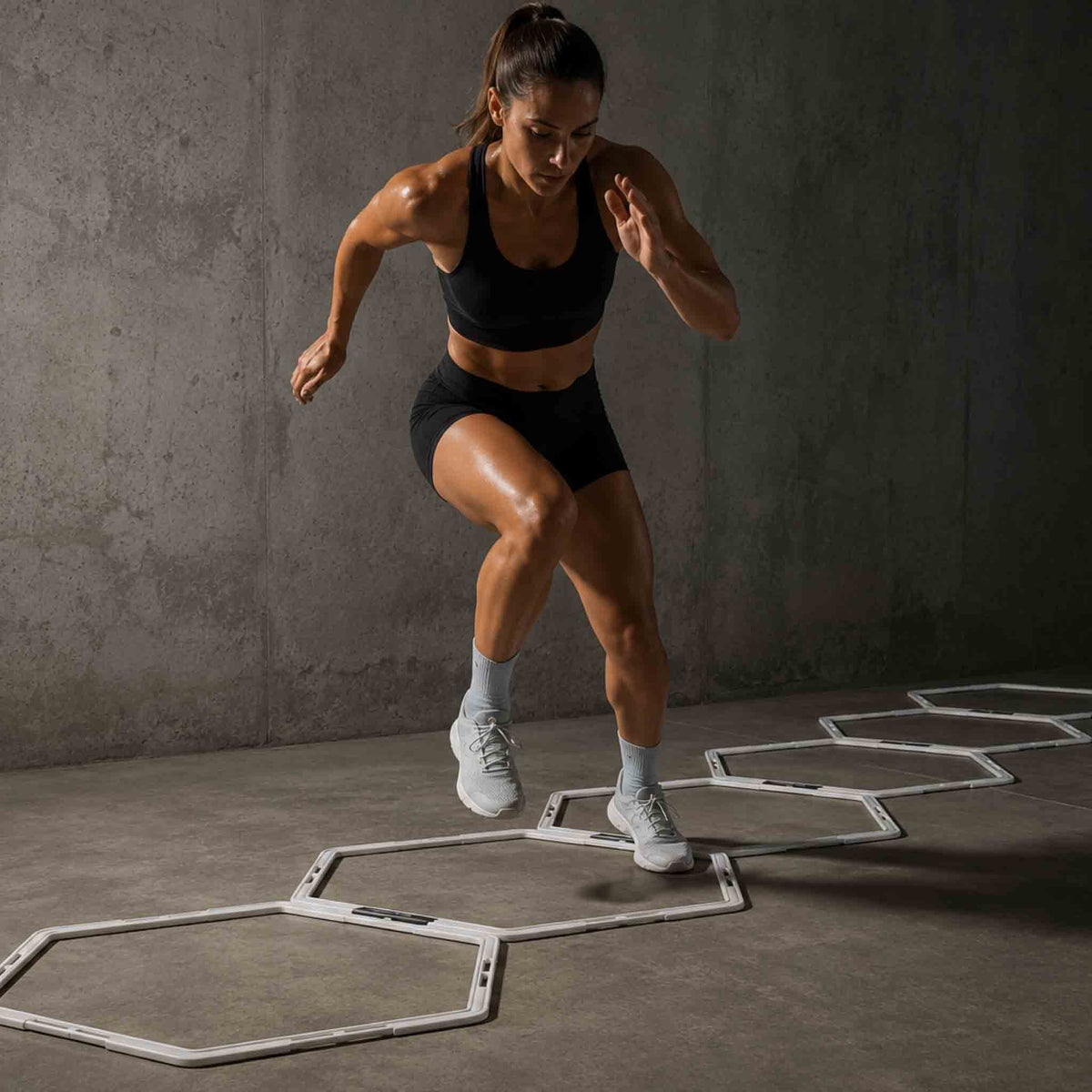 Sporter traint voetenwerk tussen plat liggende hexagon hurdles