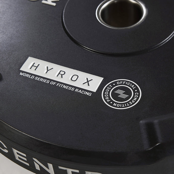 Close-up van een zwarte bumperplate met de tekst ‘HYROX WORLD SERIES OF FITNESS RACING’, een wedstrijdlogo en CENTR.