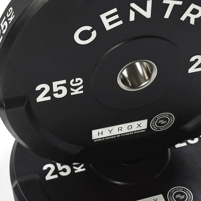 Close-up van zwarte bumperplates met de opschriften ‘CENTR’, ‘HYROX’ en ‘25 KG’.