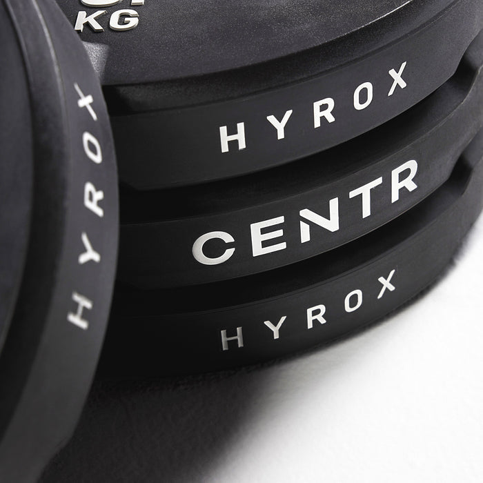 Close-up van de zijkanten van gestapelde zwarte plates met de opschriften ‘HYROX’ en ‘CENTR’.