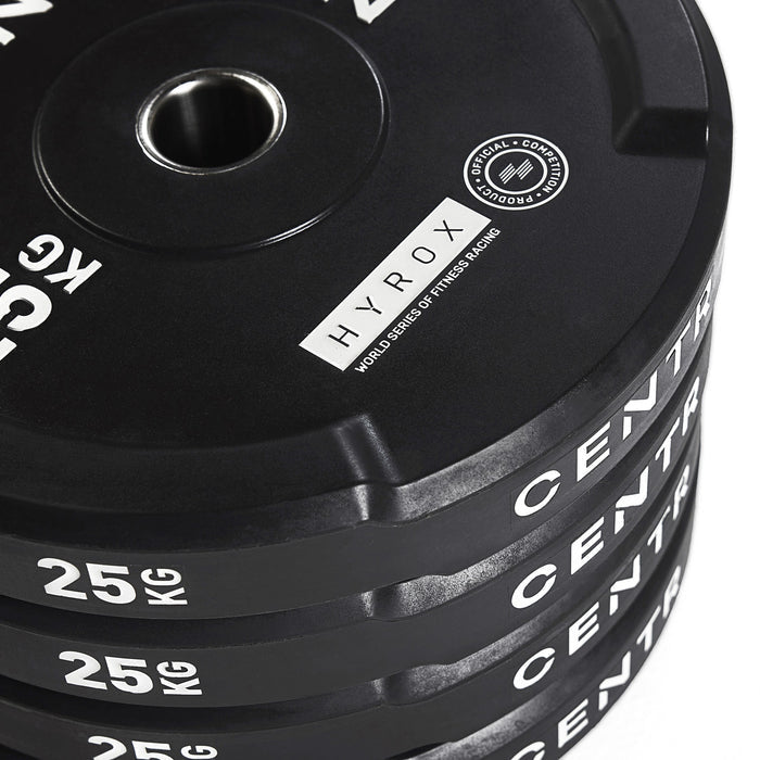 Close-up van meerdere gestapelde zwarte bumperplates met metalen middenringen en opschriften ‘25 KG’, ‘CENTR’ en ‘HYROX’.