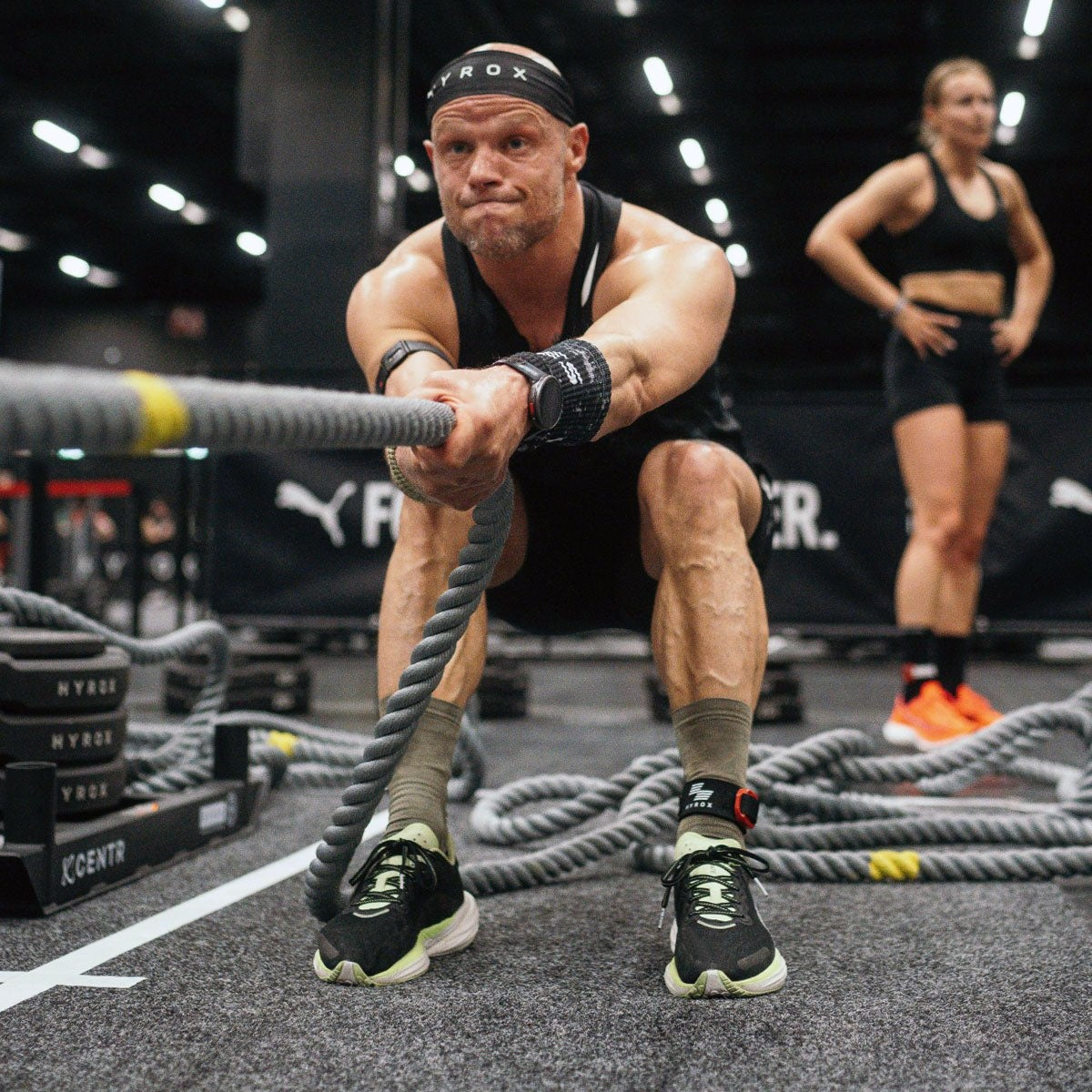 Man beweegt twee touwen in golvende banen tijdens een training.
