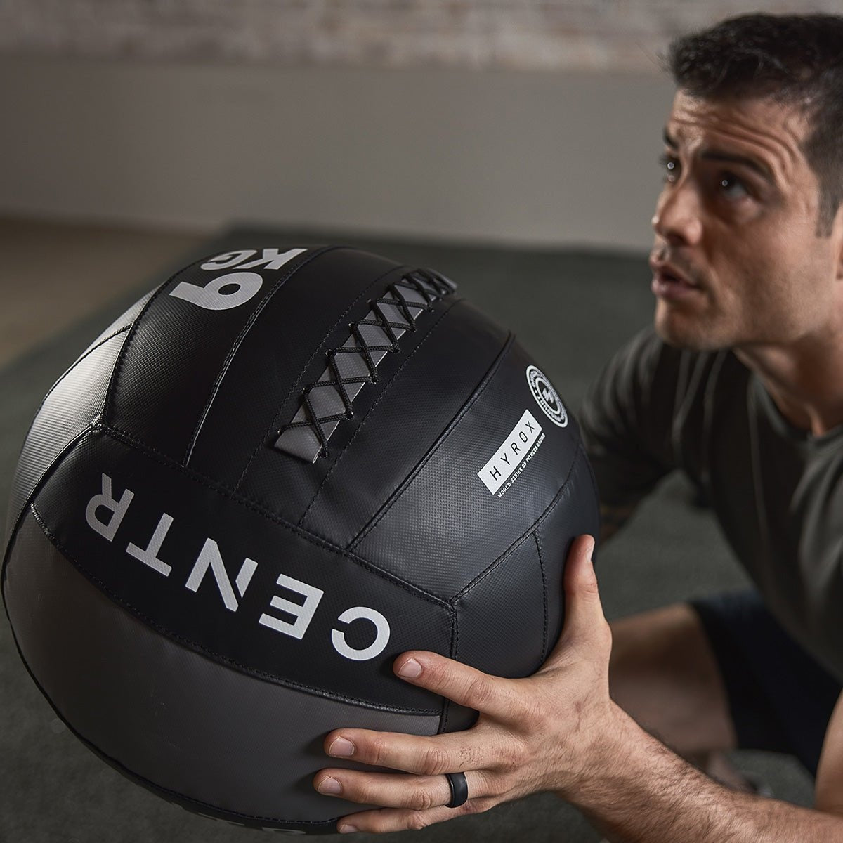 Een man houdt een zwarte trainingsbal met opschrift ‘6 KG’ voor zijn borst.