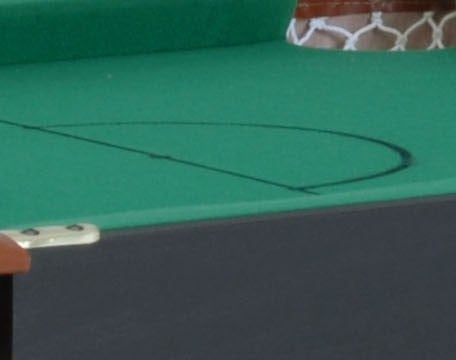 Close-up van het groene pooltafelblad met witte netpocket aan de rand.