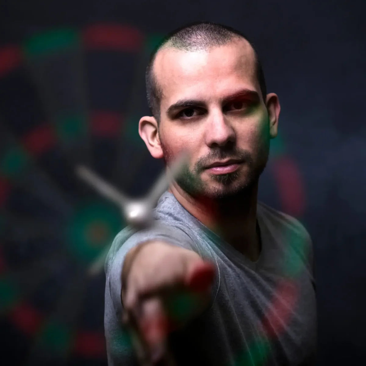 Man gooit een dart naar een dartbord; zijn hand en de dart zijn onscherp op de voorgrond.