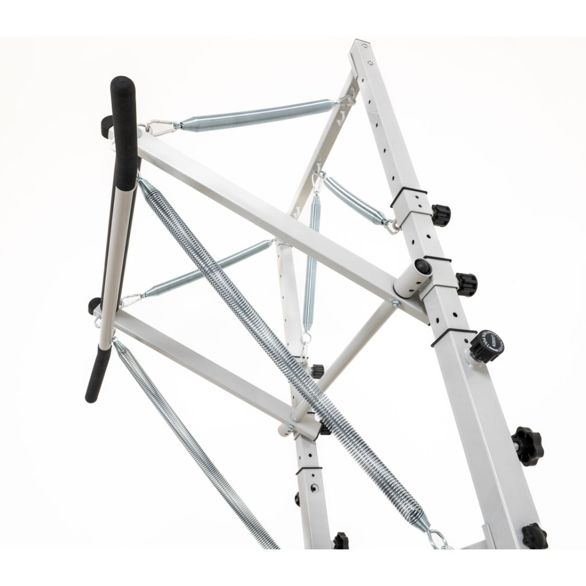 Wit metalen pilatestorenframe met zwarte handgrepen en gekruiste dwarsstangen.