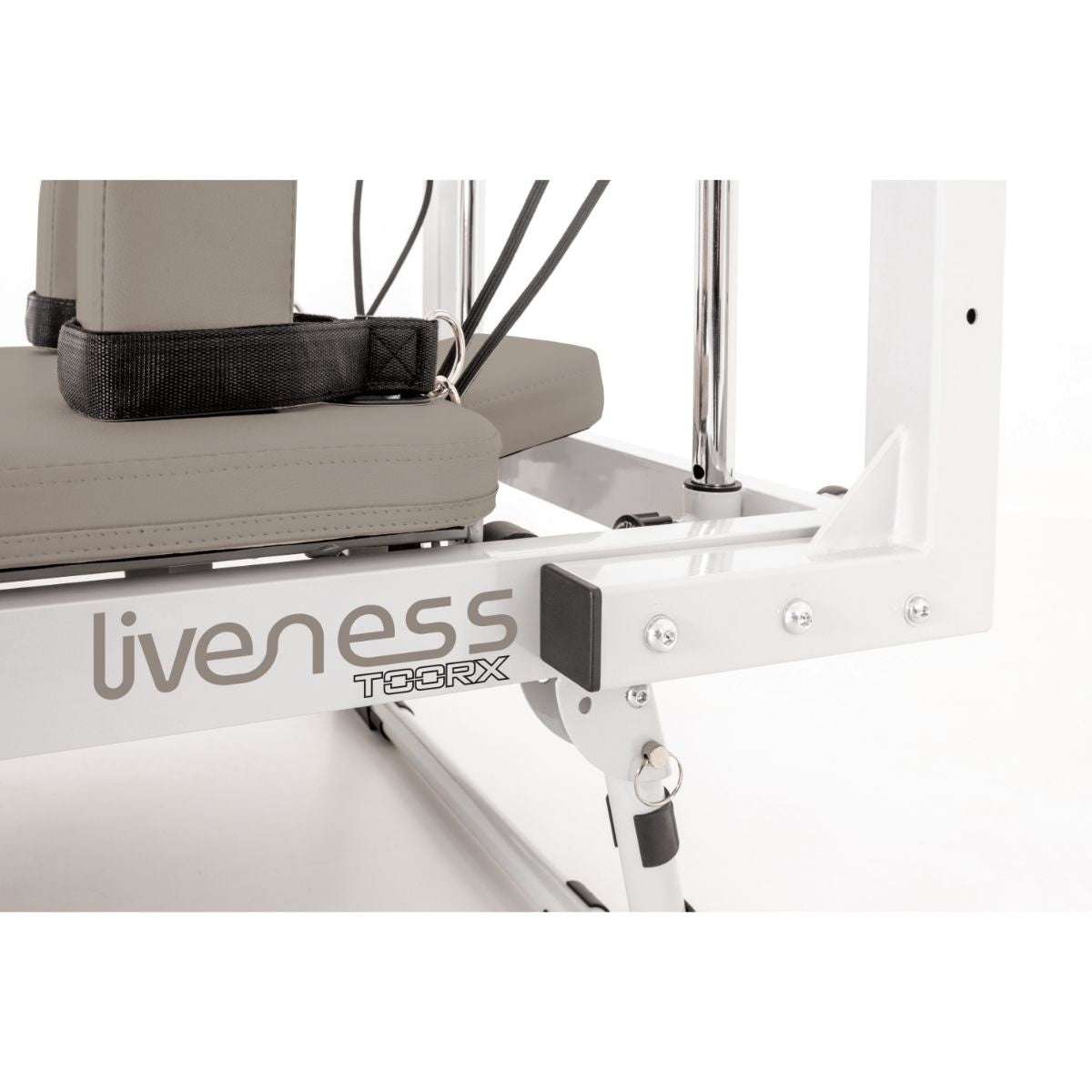 Close-up van het witte reformerframe met ‘liveness’-logo naast de zandkleurige wagen.