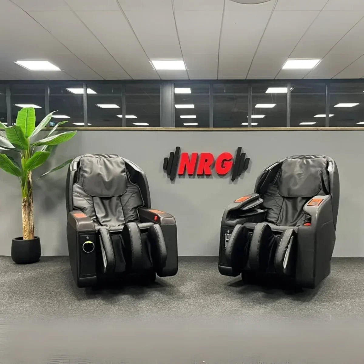 Twee zwarte NRG Wellness Commercial massagestoelen opgesteld in een showroom