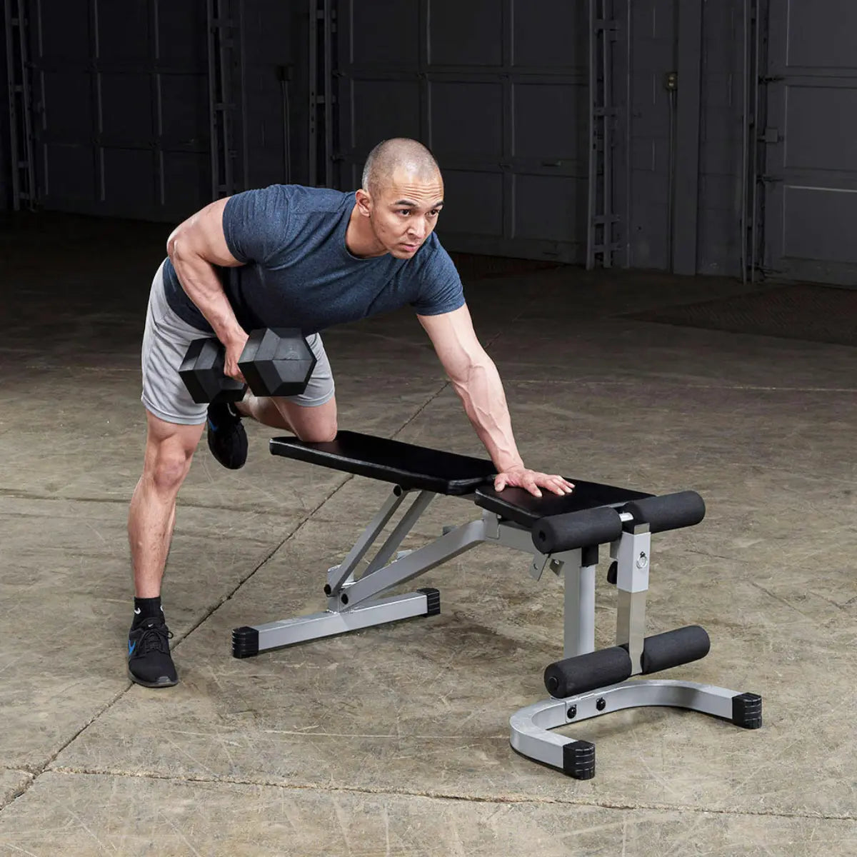 Man steunt met één hand op een bank en roeit met de andere een dumbbell.