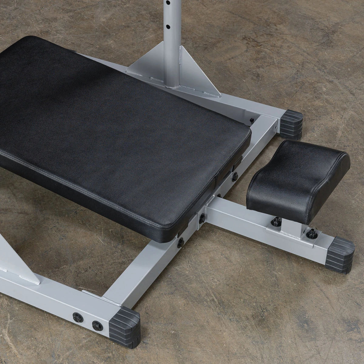Close-up of the black padded platform, foot support, and frame of a vertical leg press.
