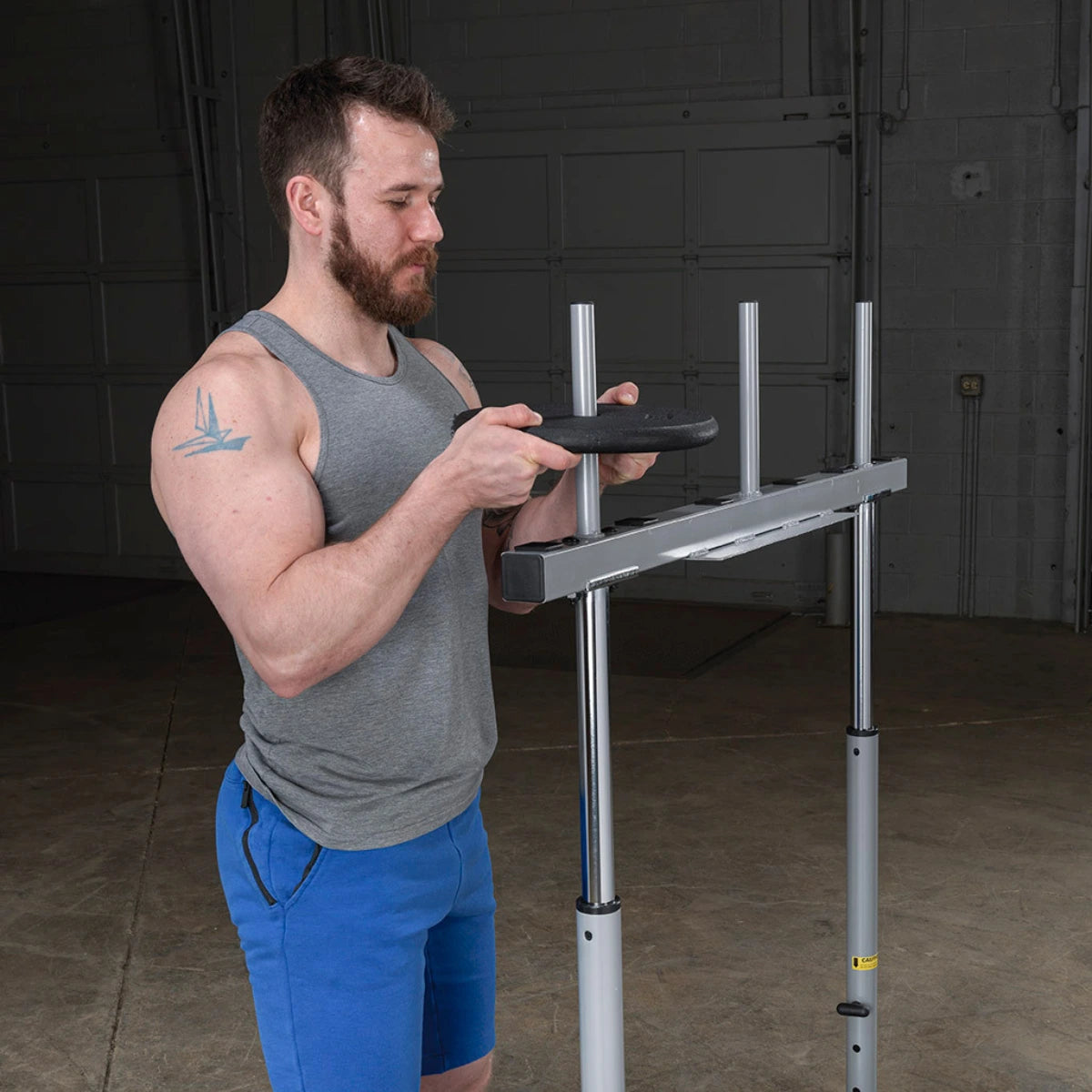 A man stands beside a vertical leg press and reaches toward the upper bar support.