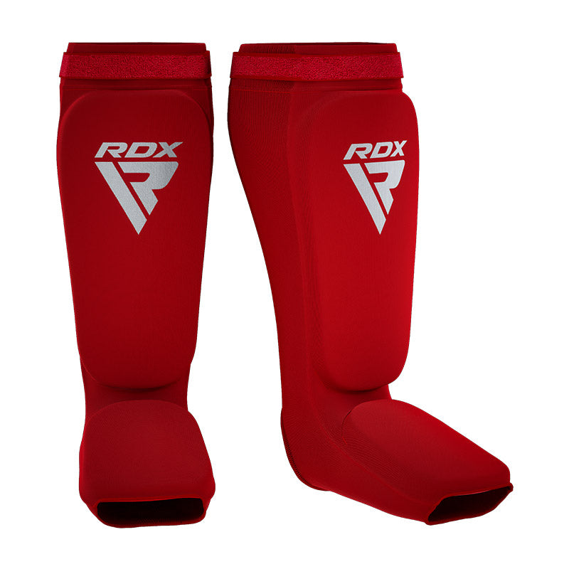 A pair of red shin and instep guards with white RDX logos against a white background.