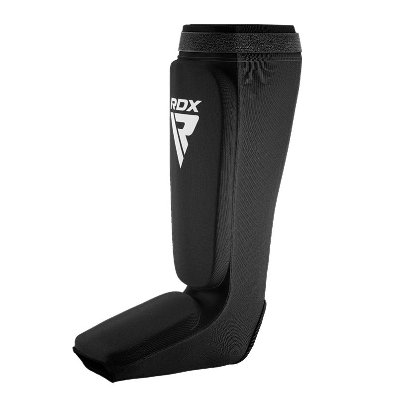 Black shin and instep guard with a white RDX logo, in side view.
