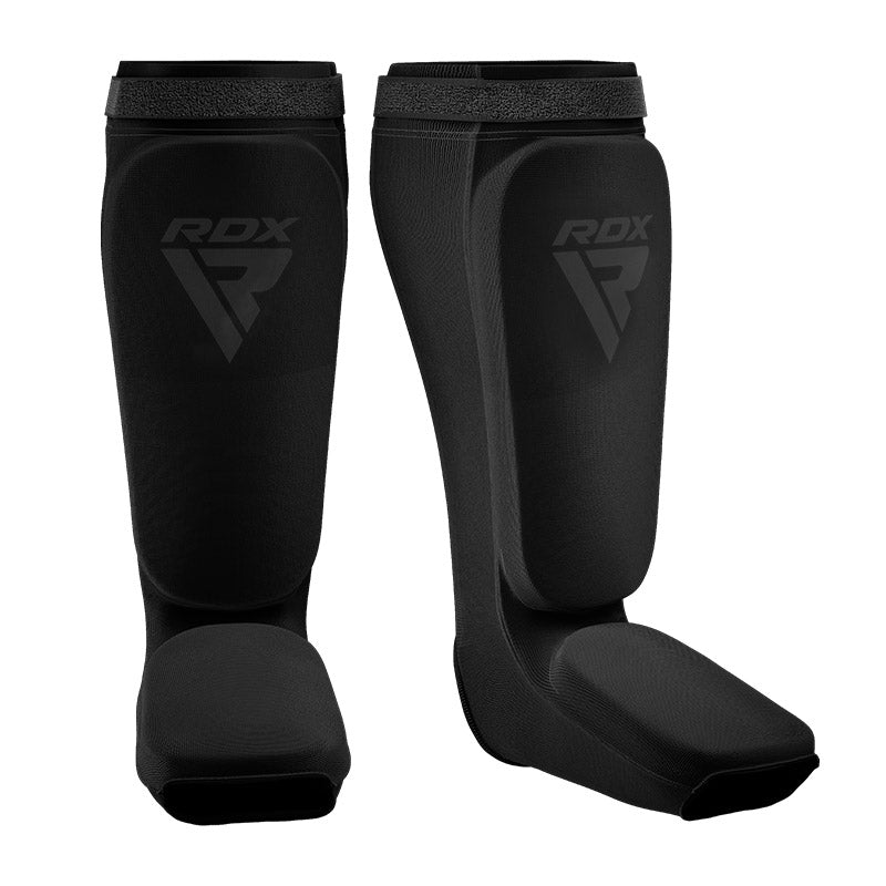 A pair of black RDX shin and instep guards with a dark logo, against a white background.