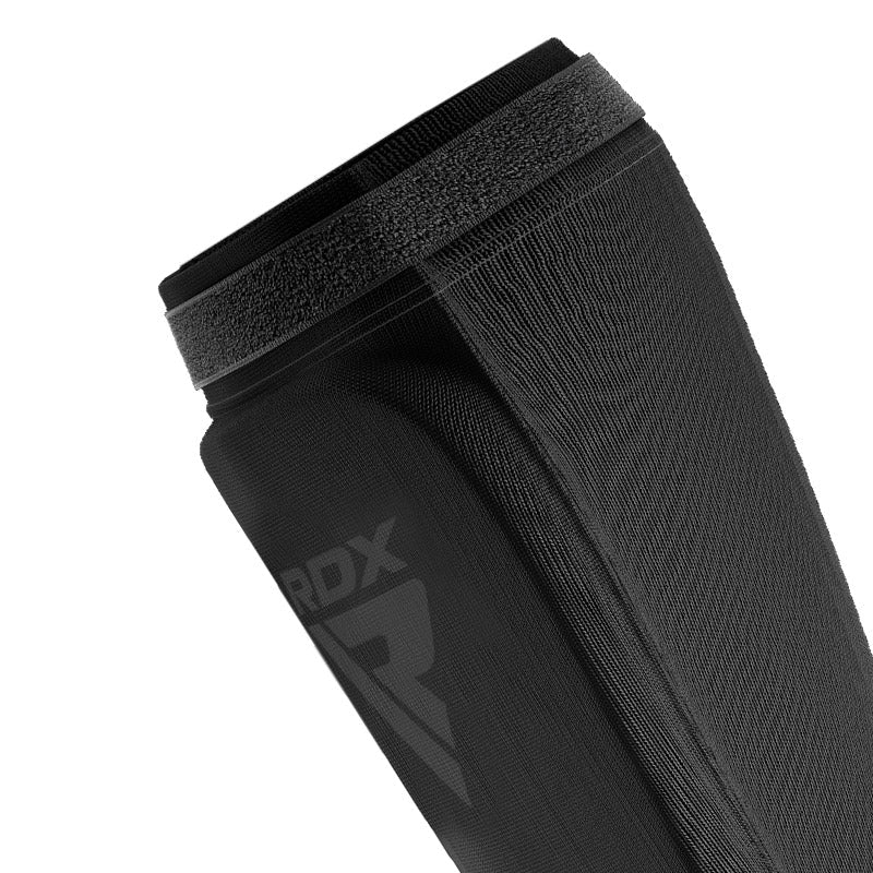 Close-up of the upper edge and fastening strap of a black shin guard.