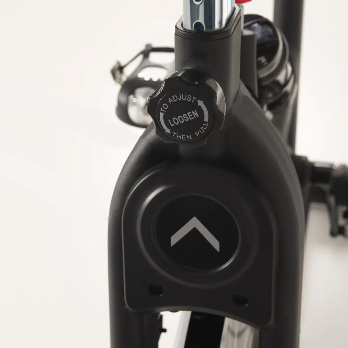 Close-up van een ronde verstelknop op het frame van een spinningfiets.