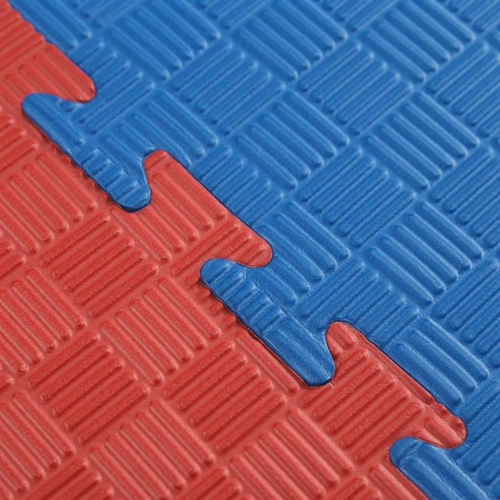Close-up van de geribbelde, in elkaar grijpende randen van rode en blauwe puzzelmatten.