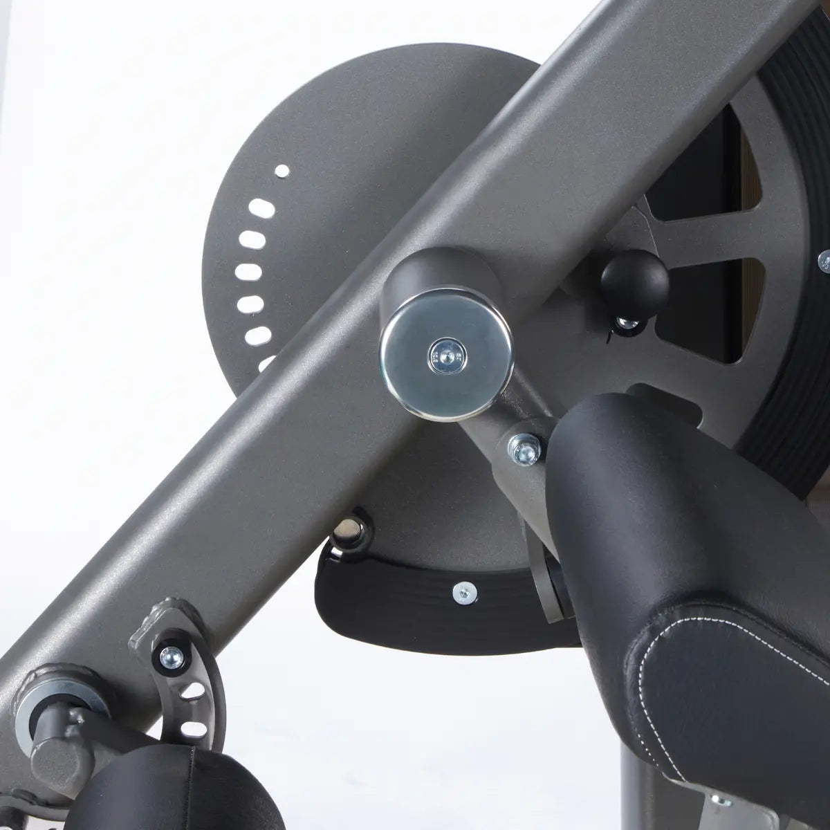 Close-up van de ronde metalen hoekversteller naast de zitting van een leg extension-machine.