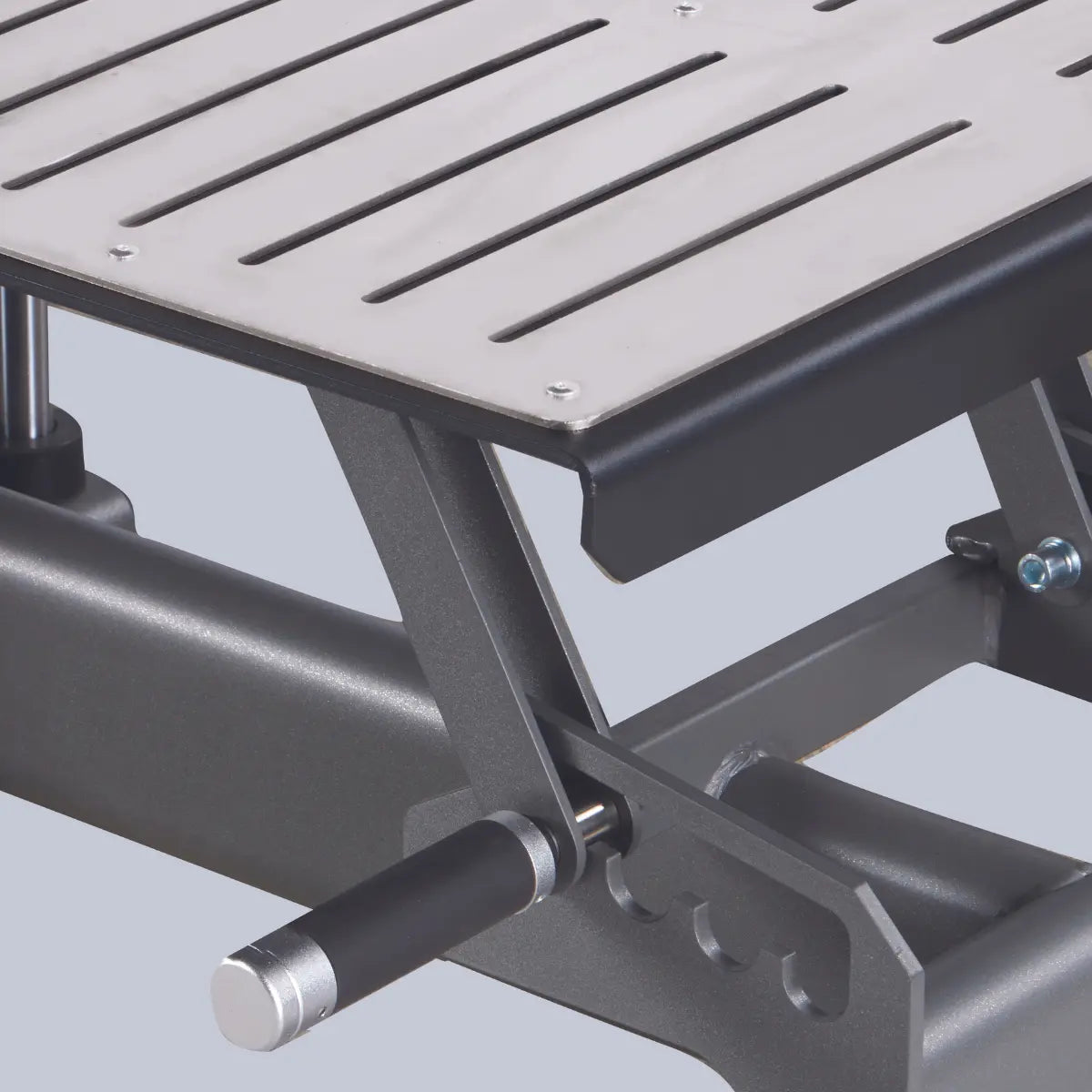 Close-up van een rechthoekige metalen voetplaat met parallelle sleuven en zwart frame.