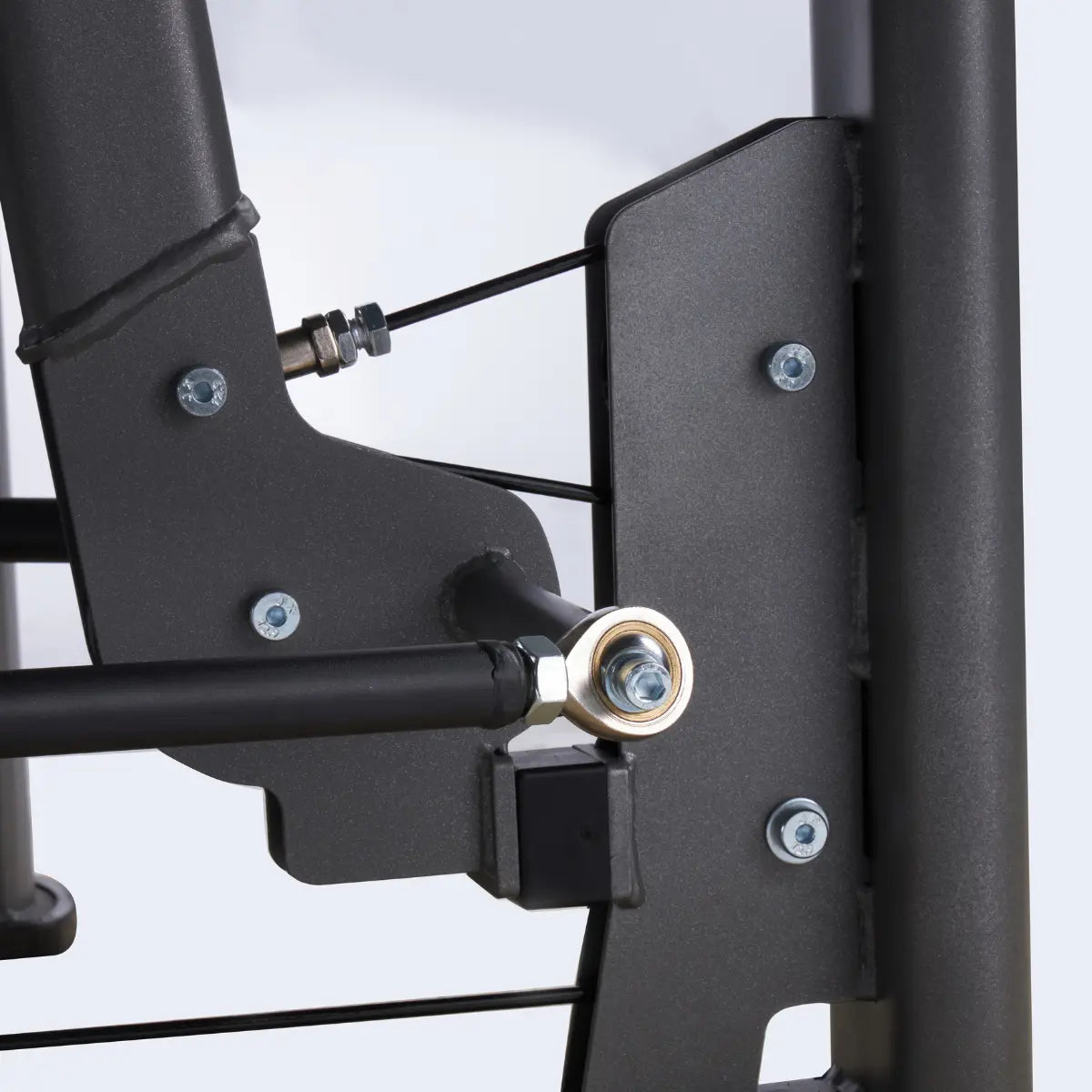 Close-up van een bevestigingspunt met bouten op het zwarte frame van een trainingsmachine.