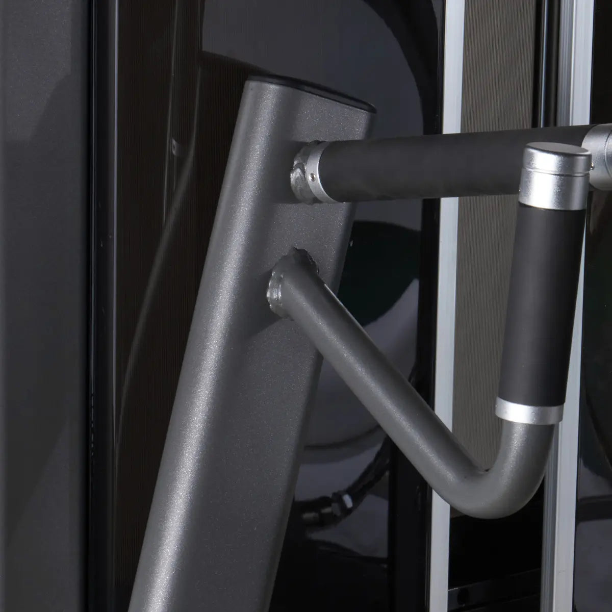 Close-up van een gebogen handgreep met metalen afwerking op een zwarte trainingsmachine.